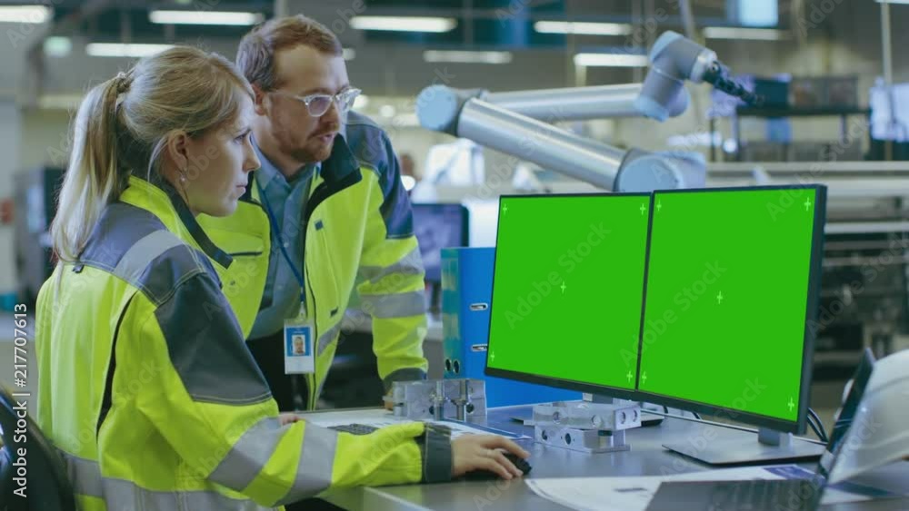 Aufkleber at the factory: male mechanical engineer and female chief engineer work together on the green mock-u