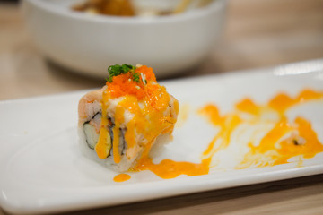 Sushi roll topped with spicy salmon slice