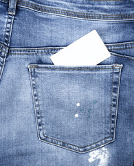 empty white paper card in the green pocket of blue jeans
