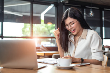 Beauty Asian woman having cheerful gesture after finishing job happily with laptop computer in cafe. People and lifestyles concept. Technology and Business working theme. Occupation and job theme.