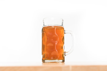 close up view of beer in mug on wooden table on white background