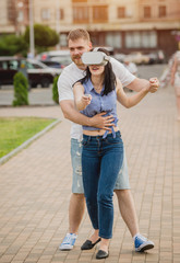Obraz premium A young couple plays a game using virtual reality glasses on the street.