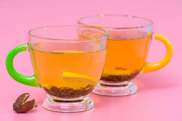 Two glass cups of spicy lemon tea or infusion on a pink background in a close up view