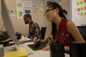 Female graphic designer using graphics tablet at desk