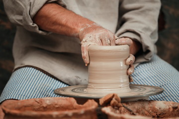 hands of a potter, creating an earthen jar on the circle 