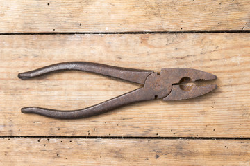 Old rusty  pliers on a wooden background