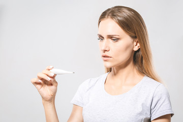 Obraz premium Portrait of a worried young beautiful woman checking her temperature. White background, flu.
