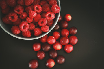 Raspberries and plums on a black table. Berries and fruit. 