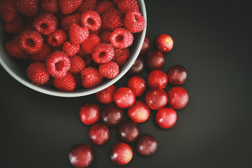 Raspberries and plums on a black table. Berries and fruit. 