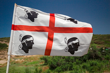 A flag of Sardinia with the four bandaged Moors waving in the blue.