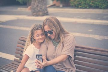 family couple mother and daughter together in outdoor happy leisure activity hugging and enjoying the day of summer before the back to school and the winter. blonde caucasian mom and girl
