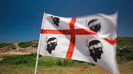 A flag of Sardinia with the four bandaged Moors waving in the blue.