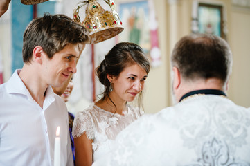 Newlyweds, couple happy at the wedding ceremony in the church. The priest blesses for a long life...