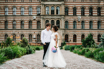 Obraz premium Portrait the groom in wedding suit and the bride in dress stand near ancient restored architecture, old building, old house outside, vintage palace outdoor.