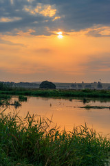 Orange sunset above small river at summer evening. River landscape