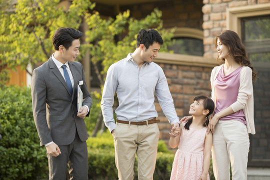 Happy young family talking with realtor
