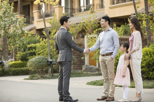 Happy young family shaking hands with realtor
