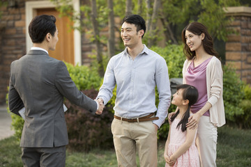 Happy young family shaking hands with realtor