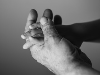 Hand of the old man and a child hand. Selective focus.