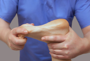 The doctor-podiatrist does an examination and massage of the patient's foot in the clinic.