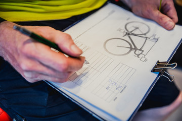 Obraz premium Bicycle setting - man in bicycle service write parameters of bike, on catalog