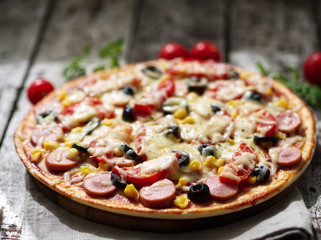 Homemade pizza with parmesan, oregano, olives and mozzarella, sausage and tomato sauce, side view, day light