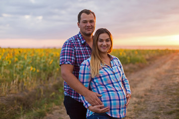 Young romantic couple in a field of sunflowers, pregnant girl in sunflowers