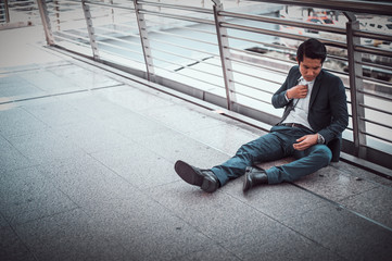 businessman unemployed from company sitting on street, he is feeling of stressed and sadness, concept of business failure and unemployment problem. with copy space for text