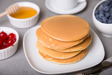 Pancakes with blueberries, cherries and honey. Close-up. Selective focus.