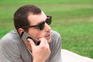 Young handsome man using mobile phone in park