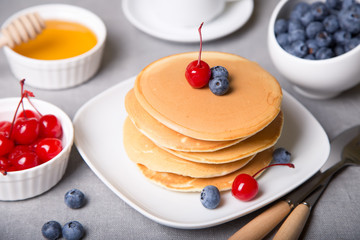 Pancakes with blueberries, cherries and honey. Close-up. Selective focus.
