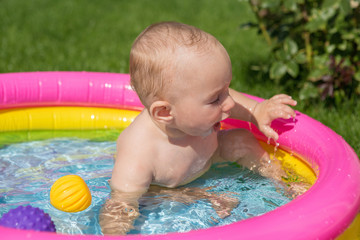 A small child is bathing in a pool, inflatable children's inflatable pool in summer	