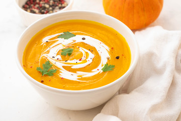 Pumpkin soup with cream and pumpkin seeds isolated on white background. Autumn concept.