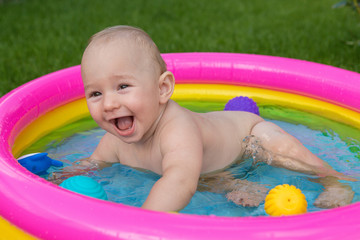 A small child is bathing in a pool, inflatable children's inflatable pool in summer	