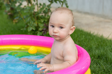 A small child is bathing in a pool, inflatable children's inflatable pool in summer	