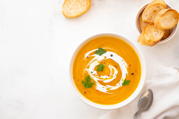 Pumpkin soup with cream and pumpkin seeds isolated on white background. Autumn concept.
