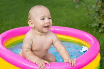 Fototapeta na wymiar A small child is bathing in a pool, inflatable children's inflatable pool in summer