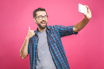 I love selfie! Handsome young man in shirt holding camera and making selfie and smiling while...