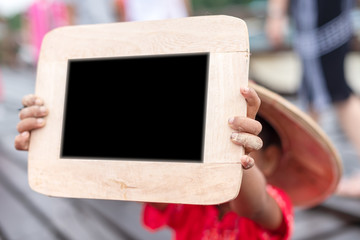Young little boy raises up a blackboard with her name on it. Young boy in primary school age happy showing blackboard on the bridge countryside.