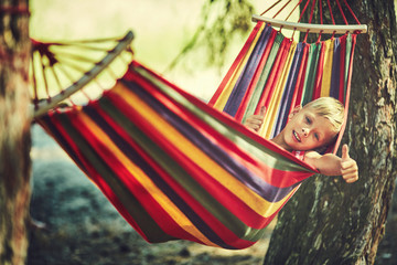 Fototapeta na wymiar Little boy resting in hammock outdoors. Summer camp