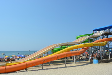 Obraz na płótnie Canvas Water slides, long pipes of green, orange and yellow on the beach of the Black Sea