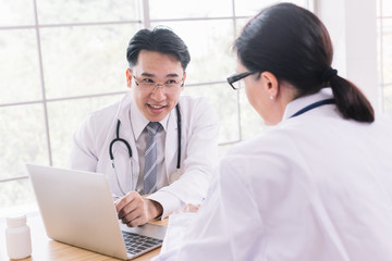 Two doctors are discussing the results of a patient's presentation of the results of a tablet computer sitting at a desk.