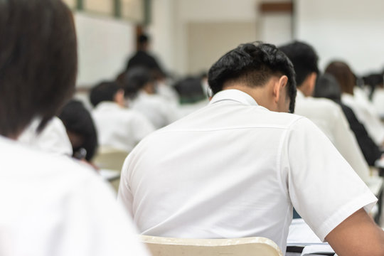 School student's taking exam, thinking hard, writing answer in classroom for educational university admission test  and world literacy day concept