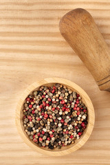 An overhead closeup photo of a mix of various peppers with a pestle, with copy space