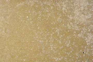 A worn-out reinforced concrete wall of greenish gray on the sunny rays