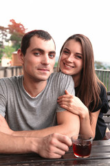 Young beautiful couple share tea at garden table