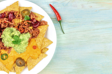 Closeup of nachos with cheese and chilli, traditional Mexican snack, with a pepper and copyspace