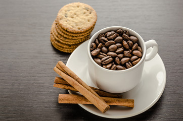 A cup of coffee with cookies and cinnamon.