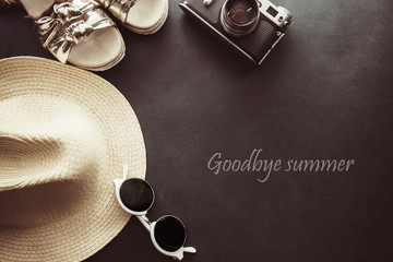 sunglasses, camera, sandals  and hat on a gray background, spell Goodbye summer 