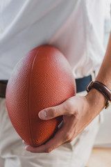 close-up partial view of businessman holding rugby ball in office